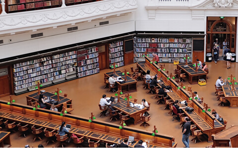 International Students sitting at tables in a library.