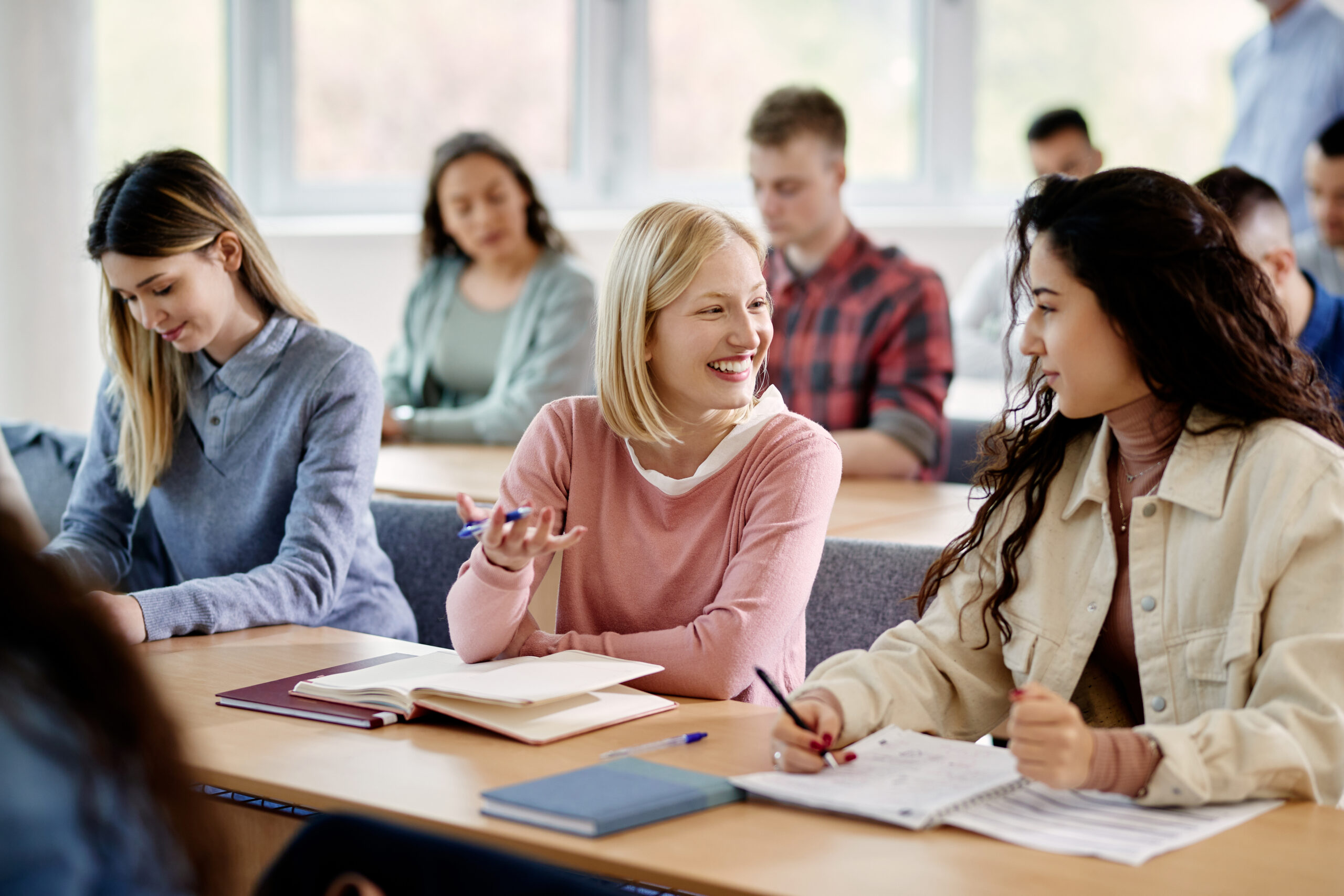 Happy female students talking while attending a lecture at the university.